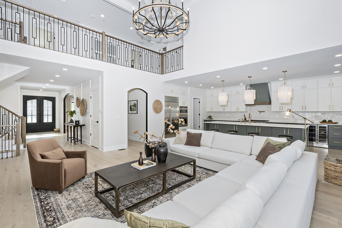 Luxury staged open concept with green cabinetry kitchen and iron railing by Homes Aglow
