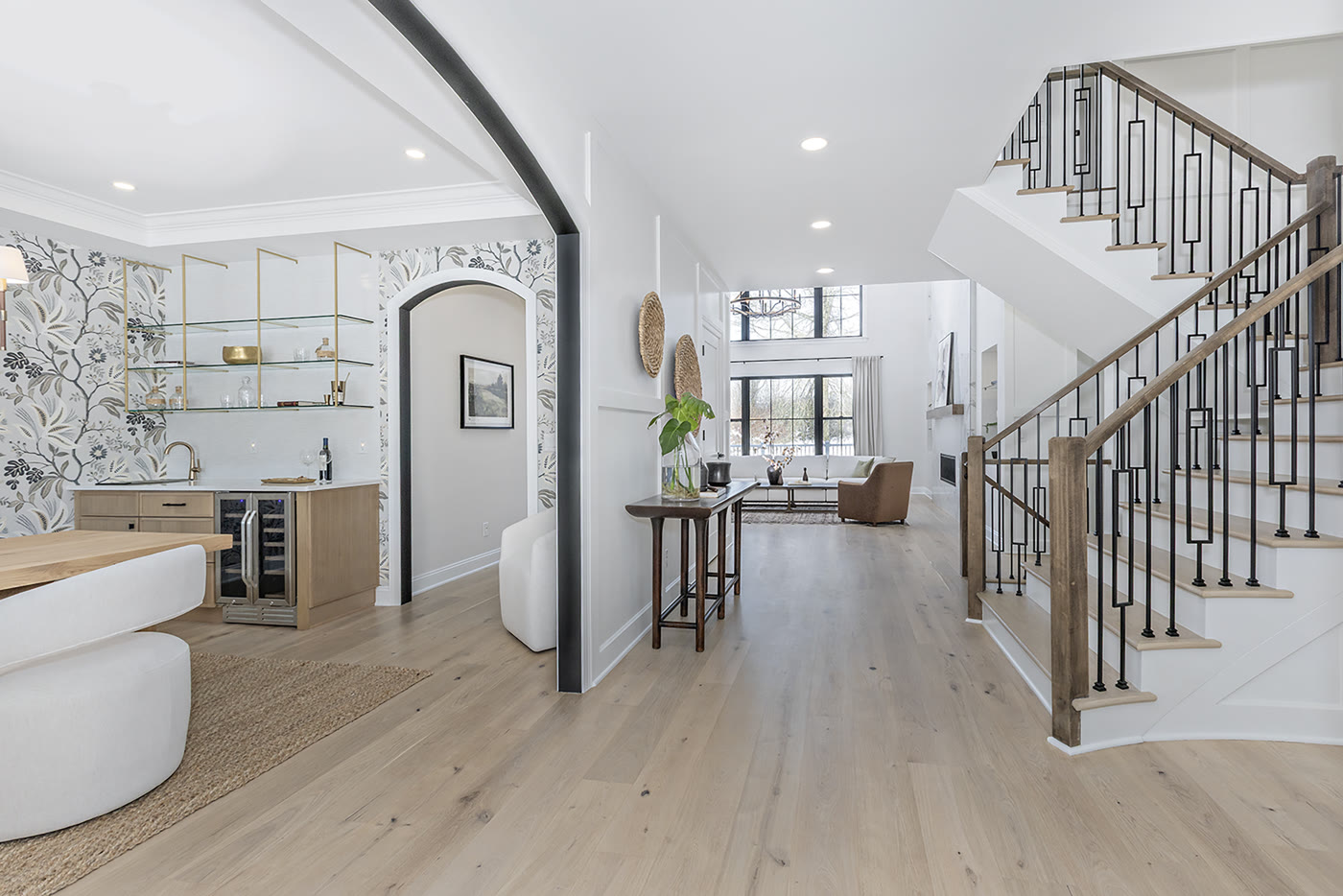 Luxury staged entryway with botanical wallpaper bar and iron staircase by Homes Aglow